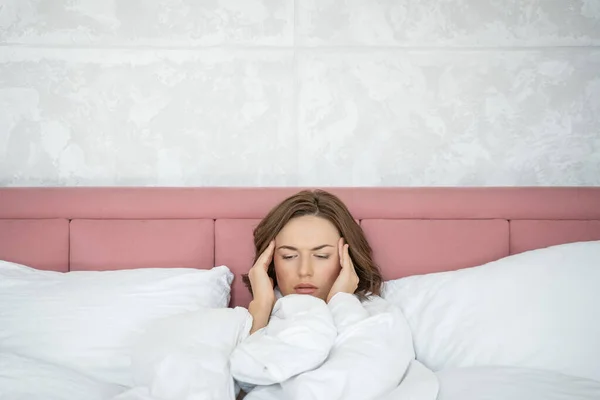 Mujer joven de espíritu bajo con dolor de cabeza acostada en la cama — Foto de Stock