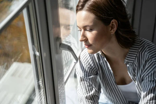 Jeune femme détendue regardant par la fenêtre — Photo