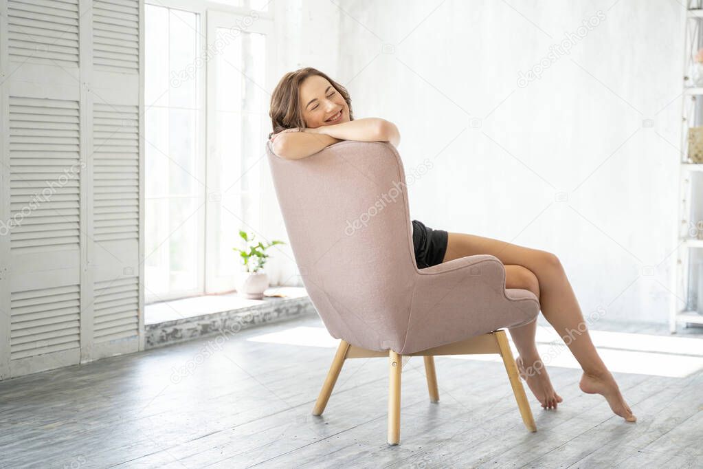 Happy female sitting in an armchair at home