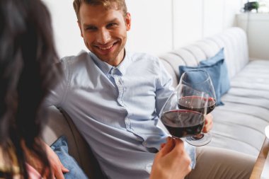 Yakışıklı genç adam ve kadın kafede kırmızı şarapla kadeh kaldırıyor.