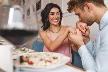 Yakışıklı genç adam, büyüleyici bayanın elini öpüyor.