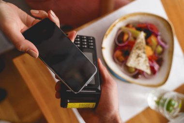 Restoranda düzeni sağlamak için akıllı telefon kullanan genç bir kadın.