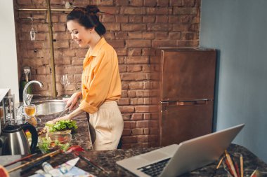 Çekici genç bayan evde yemek pişiriyor.