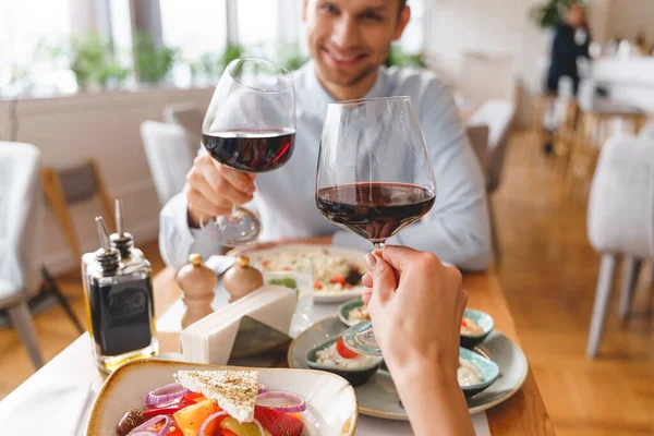 Улыбающиеся молодой человек и женщина тост с вином в ресторане — стоковое фото