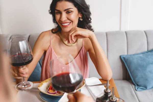 Веселая молодая женщина пьет вино с другом в кафе — стоковое фото