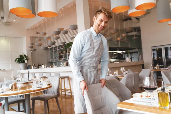 Alegre camarero masculino en delantal trabajando en restaurante —  Fotos de Stock