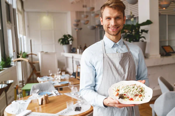 Веселий молодий чоловік тримає тарілку свіжого салату — стокове фото