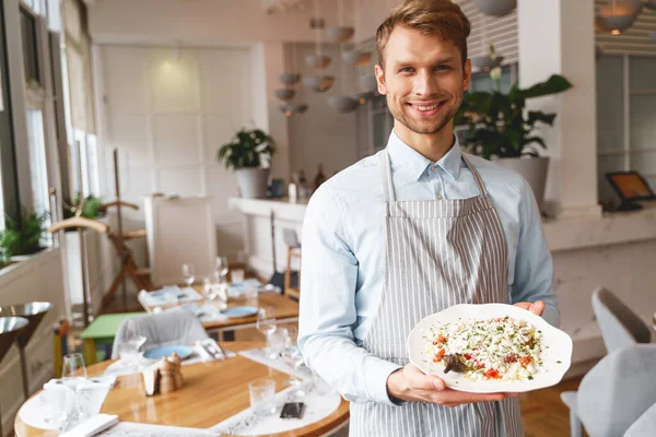 Joyeux jeune homme tenant une assiette de salade fraîche — Photo