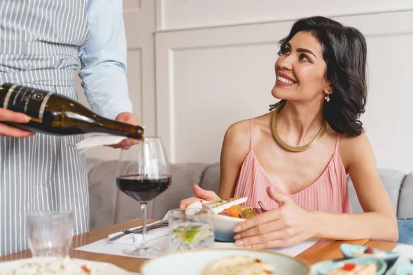 Waiter serving wine to beautiful young woman in restaurant — Stock Photo, Image