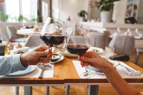 Молодой человек и женщина тост с красным вином в ресторане — стоковое фото