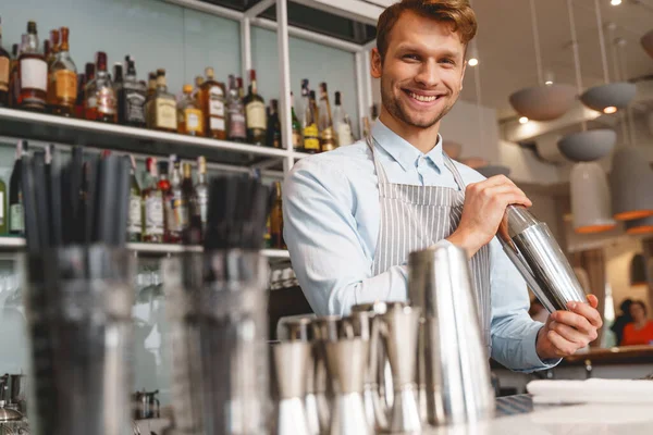 Barman alegre no avental misturando coquetel com agitador — Fotografia de Stock