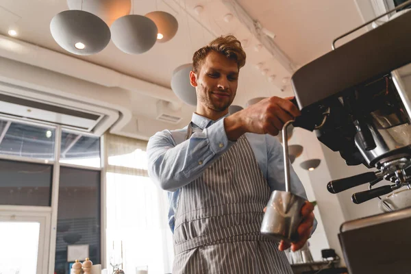 Uśmiechnięty barman w fartuchu przy użyciu profesjonalnego ekspresu do kawy — Zdjęcie stockowe