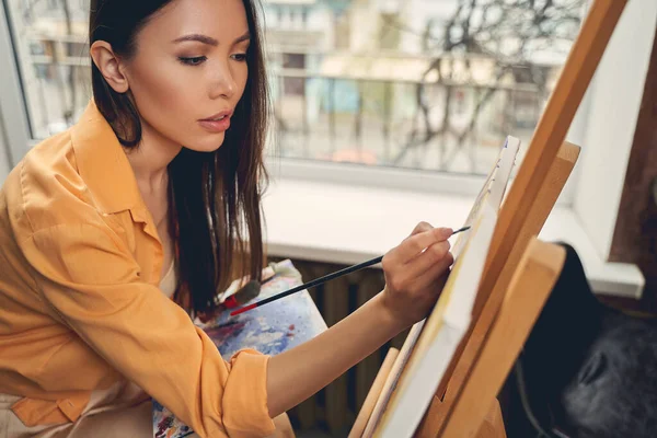Attraktive junge Frau malt Bild zu Hause — Stockfoto