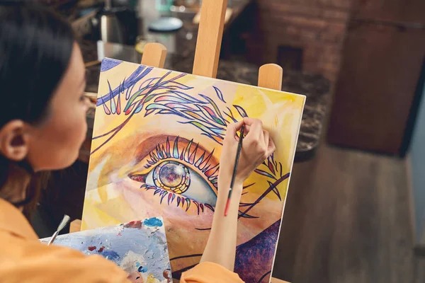 Young woman painting beautiful picture on easel at home — Stock Photo, Image