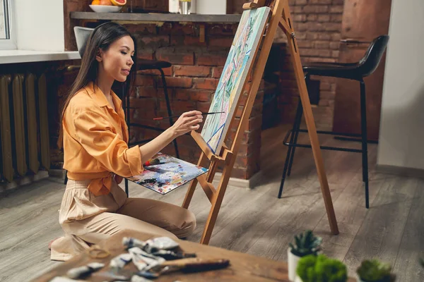 Atractiva joven mujer pintura cuadro en casa — Foto de Stock
