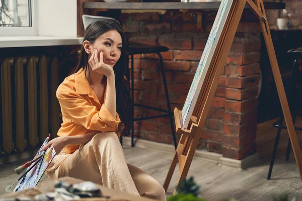 Attraktiv dam tittar på sin målning i hem konst studio — Stockfoto