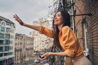 Balkonda duran neşeli bayan ve selam veren arkadaş