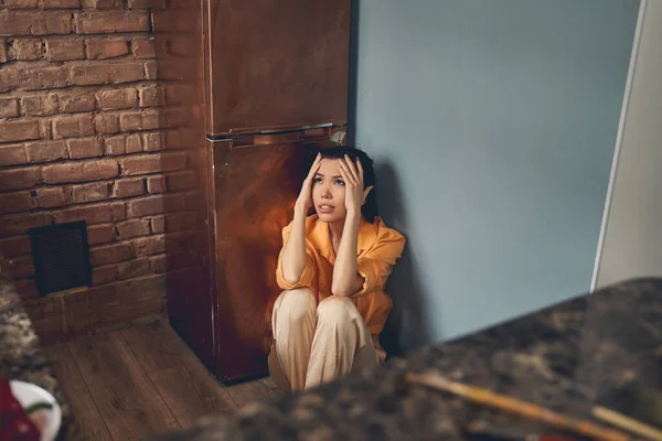 Malheureuse jeune femme assise sur le sol à la maison — Photo