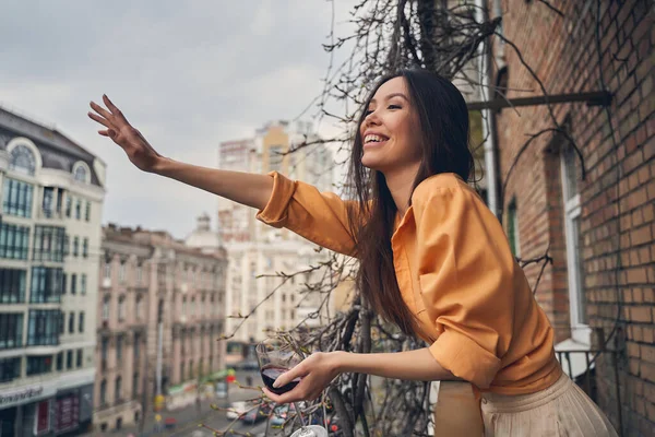 Alegre dama de pie en el balcón y amigo saludo — Foto de Stock