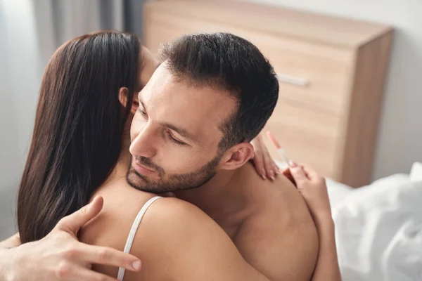 Hombre abrazando a su esposa con una prueba de embarazo —  Fotos de Stock