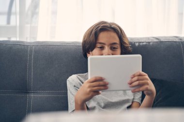 Kanepede oturan gülümseyen beyaz çocuk.