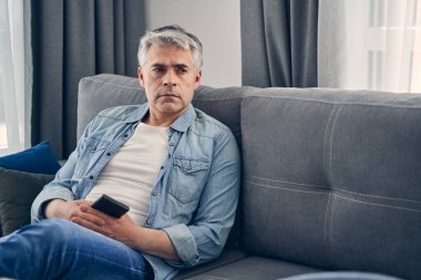 Sıradan kıyafetler giyen bir adam evde yalnız kalıyor.