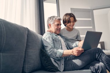 Gülümseyen baba ve oğlu birlikte vakit geçiriyorlar.