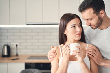 Özenli genç koca evde karısına sarılıyor.