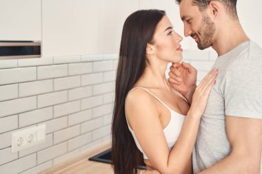 Romantik yeni evliler mutfak alanında şefkatle kucaklaşıyorlar.