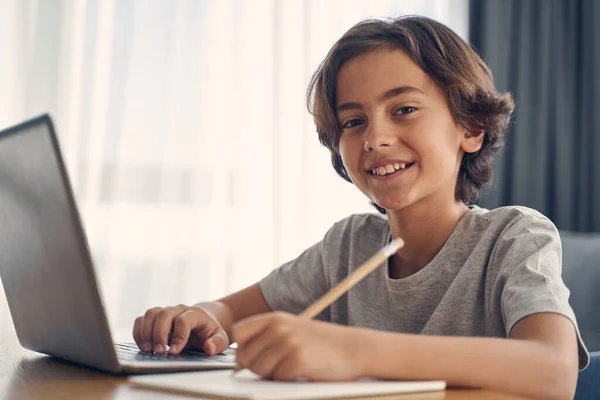 Szczęśliwy mały chłopiec uśmiecha się pisząc coś — Zdjęcie stockowe