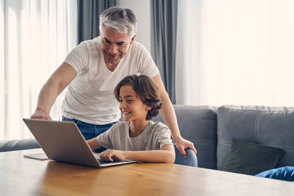 灰色の髪の父と彼の小さな子供はコンピュータを見て — ストック写真