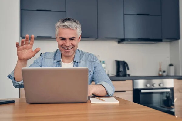 Beau homme restant à la maison et saluant pendant l'appel vidéo — Photo