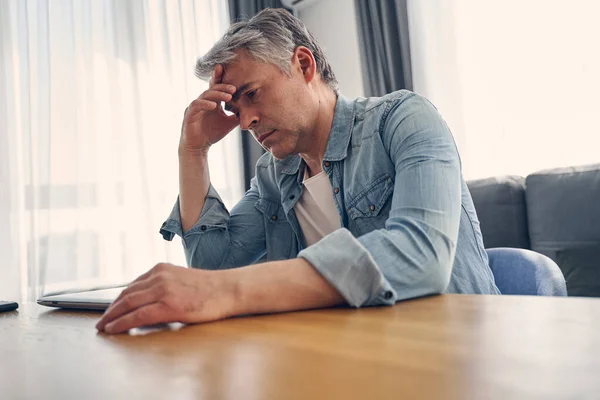 Volwassen man op zoek serieus terwijl thuis zitten — Stockfoto