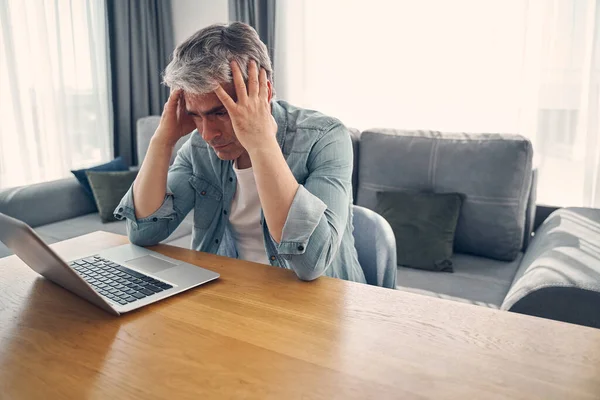 Grijze harige man die thuis zit te denken — Stockfoto