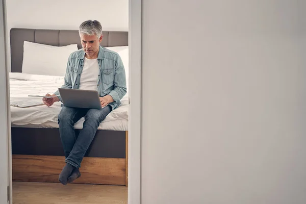 Hombre de pelo gris sentado en el dormitorio con documentos — Foto de Stock