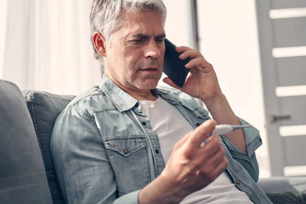 Grey haired man talking on phone at home — Stock Photo, Image