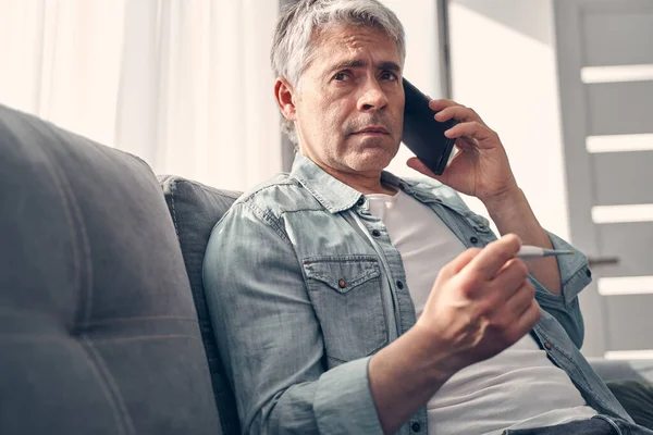 Измученный белый мужчина разговаривает по телефону дома — стоковое фото