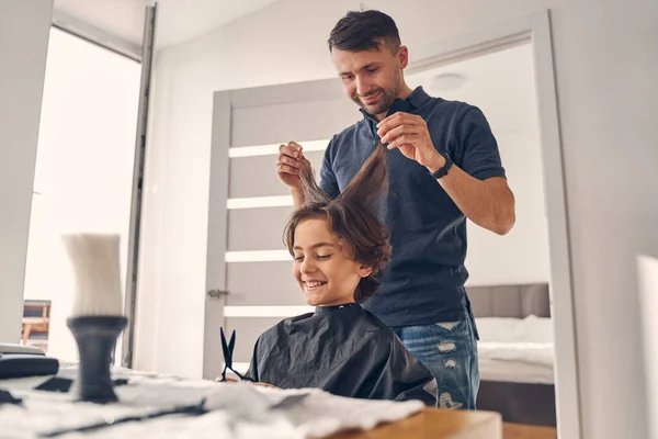 Ελκυστική νεαρή κομμώτρια αλλαγή hairstyle του παιδιού — Φωτογραφία Αρχείου