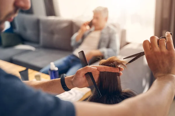 Joven cortándose el pelo con tijeras y peine — Foto de Stock