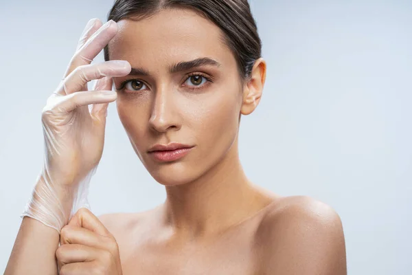 Feminino puxando uma luva descartável em sua mão — Fotografia de Stock