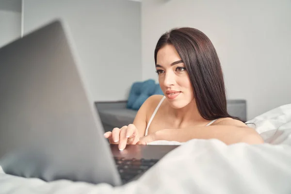 Bastante hembra de pelo largo mirando en la pantalla de la computadora portátil — Foto de Stock