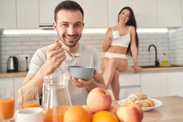 Szczęśliwy młody człowiek je śniadanie z żoną w domu — Zdjęcie stockowe