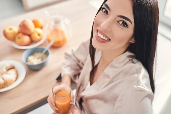 Ωραία χαμογελαστή νεαρή γυναίκα που τρώει υγιεινό πρωινό στο σπίτι — Φωτογραφία Αρχείου