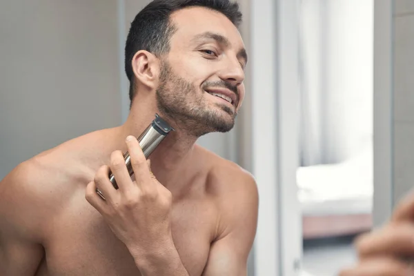 Sorrindo jovem barbear rosto na frente do espelho — Fotografia de Stock