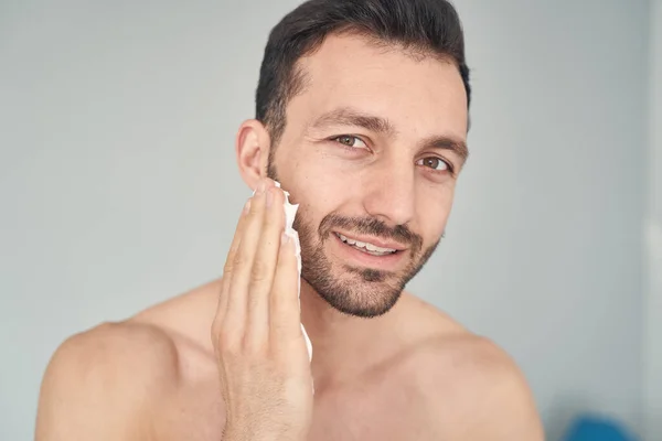 Joven positivo sonriendo antes de comenzar el procedimiento de afeitado — Foto de Stock