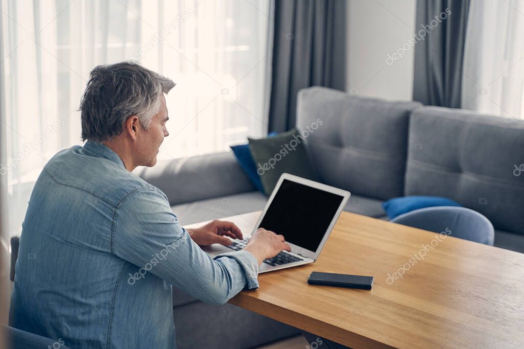 Grey-haired male staying at home with computer