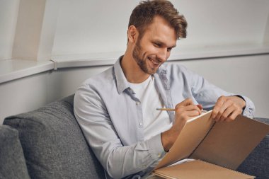 Genç adam not defterine not alıyor.