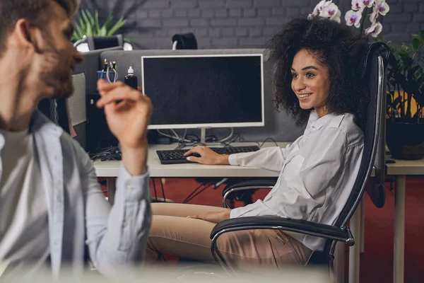 Alegre mujer rizada sonriendo a su colega — Foto de Stock