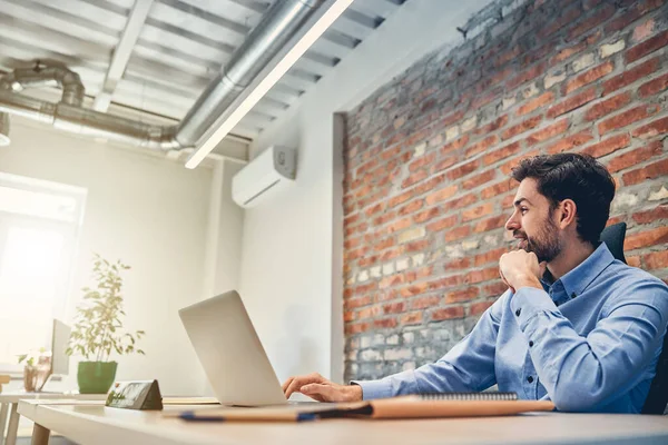 Feliz hombre de negocios está utilizando el ordenador portátil en el trabajo — Foto de Stock