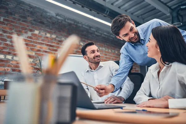 Compañeros de trabajo sentados en el escritorio de la oficina con computadoras portátiles y hablando — Foto de Stock